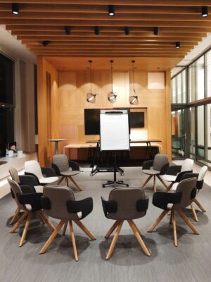 A modern conference room featuring circular seating and a flip chart, ideal for meetings and presentations.