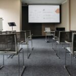 An empty conference room with chairs, a projector screen, and presentation setup.